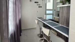 A modern kitchen with a bar area, stainless steel appliances, and a large mirror. - Villa De Gloria II - Elevated Signature Stay (Bayamon)