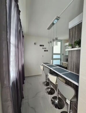 A modern kitchen with a bar area, stainless steel appliances, and a large mirror. - Villa De Gloria II - Elevated Signature Stay (Bayamon)