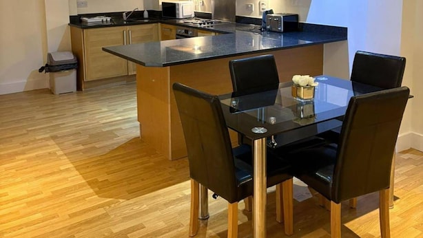 A modern kitchen with a central island, black chairs, and a glass table. - London Brigde Luxurious Spacious Apartment (London)