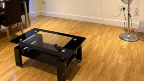 A modern glass-top coffee table with metal legs in a room with wooden flooring. - London Brigde Luxurious Spacious Apartment (London)