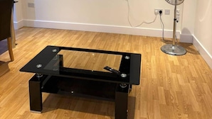 A small black table with a glass top, two metal legs, and a remote control on it. - London Brigde Luxurious Spacious Apartment (London)