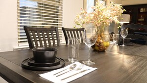 A dining table set with a bowl, cutlery, a vase with flowers, and wine glasses. - 4-bedroom house in adorable Midland  (Midland)