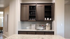 A kitchen with dark wooden cabinets, a granite countertop, and a coffee maker. - 4-bedroom house in adorable Midland  (Midland)