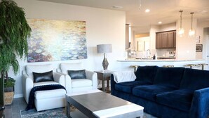 A modern living room with a sofa, coffee table, and a painting on the wall. - 4-bedroom house in adorable Midland  (Midland)