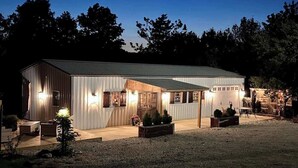 Een gebouw van metaal met een overdekte veranda, buiten zitplaatsen en een garage.