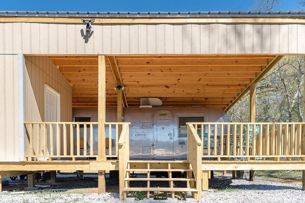 A wooden cabin with a porch, a door, and a window.