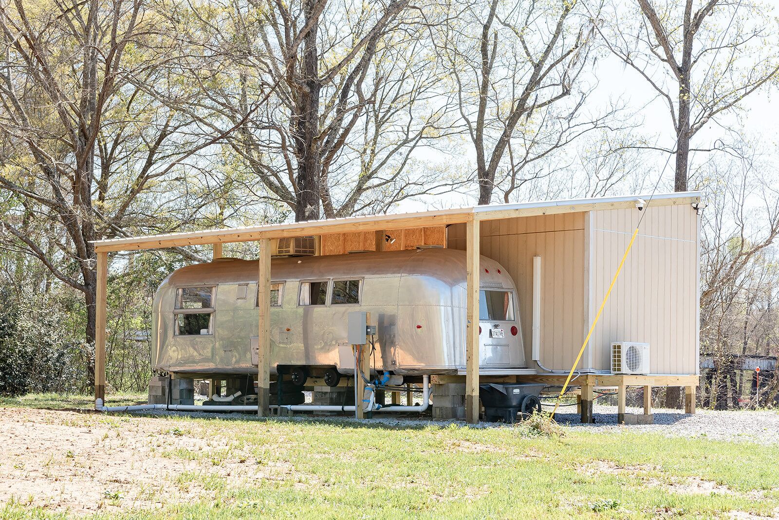 Un wagon de train immobilisé, transformé en espace de vie permanent, avec une structure en bois au-dessus.