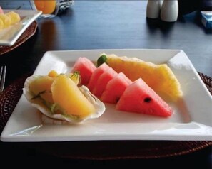 Une assiette garnie de tranches de pastèque, d’ananas et de mangue.