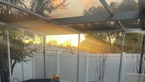 Un espacio de estar al aire libre cubierto, con una mesa redonda y sillones cómodos.