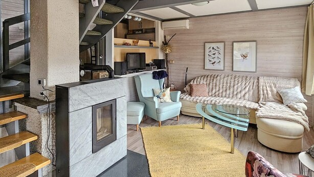 A modern living room with a fireplace, a staircase, a sofa, and a coffee table.