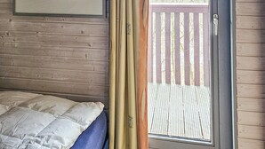 A bedroom with a bed, a door to a balcony, and a framed picture on the wall.