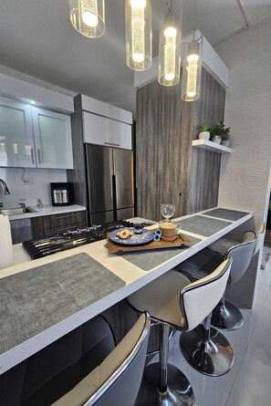 A modern kitchen with a central island, stainless steel appliances, and pendant lighting. - Villa De Gloria - Luxury Stay - Memorable Experiences (Bayamon)