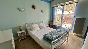 A bedroom with a bed, bedside tables, a window with curtains, and a view of the outside. - Résidence Terrasses de l'Océan Apartment terrace and pking near beach (CAPBRETON)