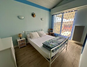 A bedroom with a bed, bedside tables, a window with curtains, and a view of the outside. - Résidence Terrasses de l'Océan Apartment terrace and pking near beach (CAPBRETON)