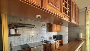 A kitchen with wooden cabinets, a washing machine, and a microwave. - Résidence Terrasses de l'Océan Apartment terrace and pking near beach (CAPBRETON)