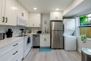 A modern kitchen with white cabinets, stainless steel appliances, and a blue mat on the floor. - Roaring Palms - Open, Airy, Perfectly Located (Sarasota)