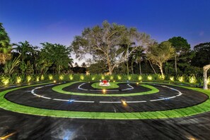 A circular driving course with a central red structure, surrounded by greenery and trees. - Unique Private Racing Track Villa (North Miami)