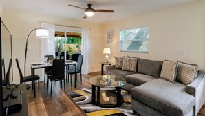 Ein Wohnzimmer mit einer Couch, einem Couchtisch, einem Esstisch, Stühlen und einem Deckenventilator.