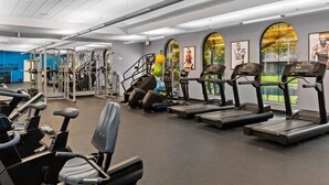 Un gimnasio con cintas de correr, elípticas y equipo de levantamiento de pesas.