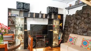 Ein Wohnzimmer mit Fernseher, schwarzen Regalen, einer Couch und einer Steinwand.