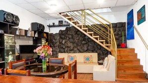 Ein Wohnzimmer mit rundem Tisch, einer Couch, einer Treppe mit Holzbalkon und einer Steinwand.