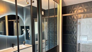 Ein modernes Badezimmer mit einem großen Spiegel, einem Waschbecken und einer Duschkabine.