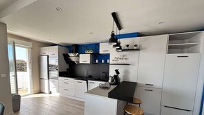 Eine moderne Küche mit weißen Schränken, einer schwarzen Arbeitsplatte und einer zentralen Kochinsel mit Sitzgelegenheiten.
