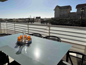 A table with a tray of glasses and a pitcher, outdoor seating with chairs, a white railing, and buildings in the background. - Renovated 3-Bedroom Apartment for 6 - Ocean View in Biscarrosse Plage (BISCARROSSE PLAGE)