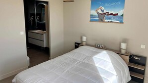 Ein Schlafzimmer mit einem Bett, Nachttischen, einer Hängelampe, einem Spiegel und einem Wandbild.
