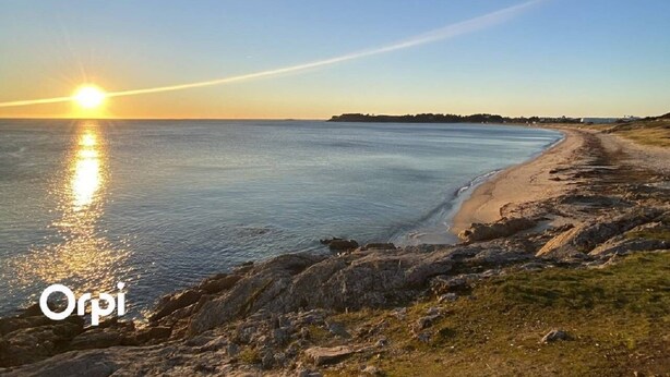 Ett kustlandskap med en strand, en klippig kustlinje och en klar himmel.