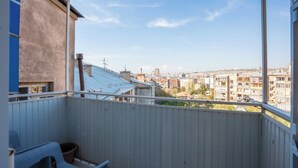 Ein Balkon mit Blick auf eine Stadtansicht, einem Holzzaun und einem Stuhl.