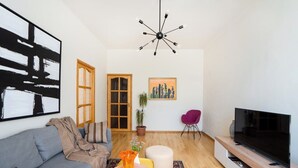 Ein modernes Wohnzimmer mit Sofa, Fernseher, Kunstwerken und einer Pflanze.