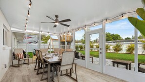 Un patio couvert avec une table à manger, des chaises et un ventilateur de plafond.