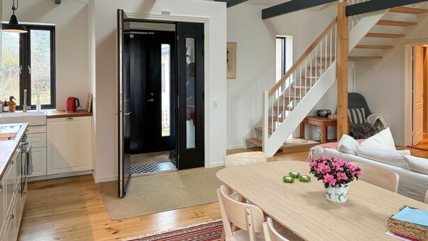 Une cuisine moderne avec un coin repas, un escalier et une vue sur l’extérieur.