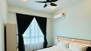 A hotel room with a bed, a ceiling fan, a window with curtains, and an air conditioning unit.