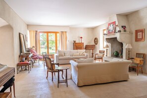 A spacious living room with a sofa, chairs, a piano, and a fireplace. - Maison Margerie - Provencal farmhouse with swimming pool and view of Mont Ventoux (Colonzelle)