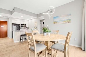 A modern kitchen with white cabinets, a central island, and a dining area with a round wooden table and four chairs. - Luau II 6631 (Miramar Beach)