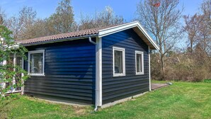 Una piccola casa a un piano con facciata blu scuro, modanature bianche e tetto in tegole.