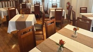 Un restaurant avec plusieurs tables et chaises, un extincteur et un tableau accroché au mur.