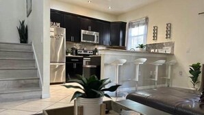 Una cocina moderna con armarios oscuros, electrodomésticos de acero inoxidable y una isla central con taburetes de bar.