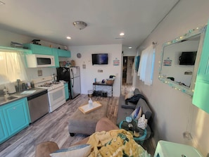 Ett kompakt bostadsutrymme med ett litet kök, en soffa, ett soffbord och en tv.