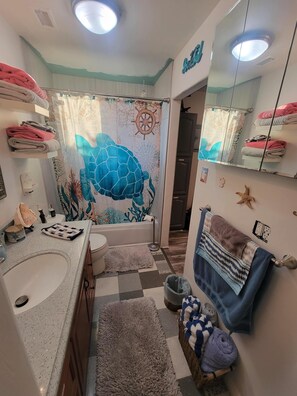 Une salle de bain dotée d’un grand miroir, de deux lavabos, d’une baignoire et d’une fresque murale décorative.