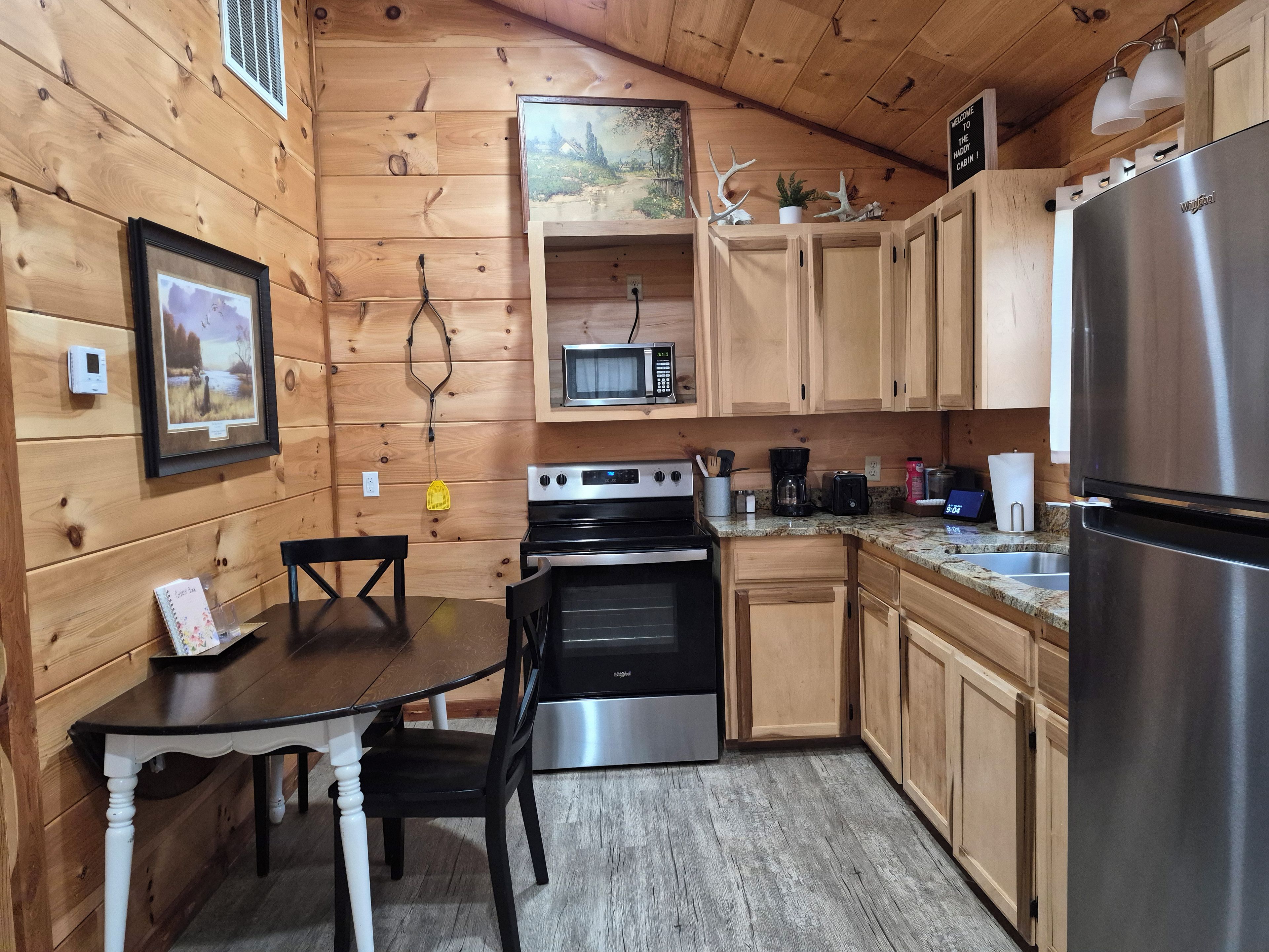 Une cuisine aménagée dans le style d’un chalet en bois, avec une table à manger, des chaises, un fourneau, un four à micro-ondes et un réfrigérateur.