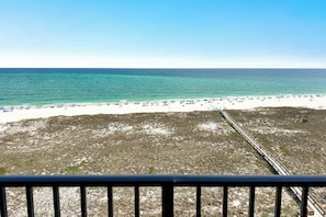 Ein Strand mit einer durch den Sand verlaufenden Bahngleis, ein klarer Himmel und das Meer im Hintergrund.