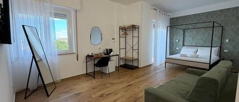 Een moderne kamer met een bed, een groene bank, een bureau en een staande lamp.