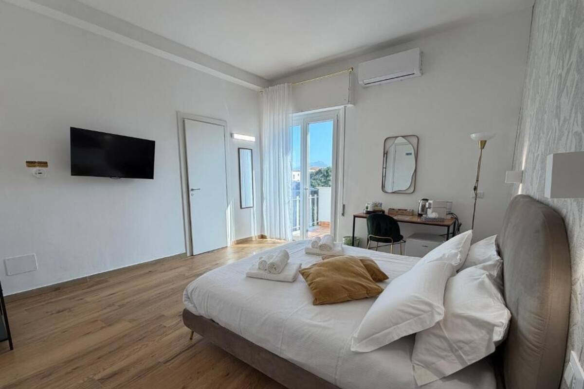 A bedroom with a bed, a flat-screen TV, a desk, and a chair.