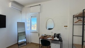 Une pièce comprenant un lit, un bureau, une chaise, un miroir, une fenêtre avec des rideaux et une armoire.