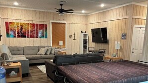 Een woonkamer met een bank, een salontafel, een televisie en een bar met barkrukken.