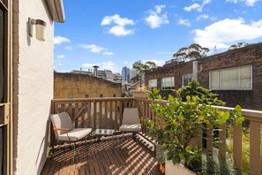 A balcony with wooden flooring, two chairs, and a potted plant. - Stylish Calm Inner City Sanctuary (Surry Hills)