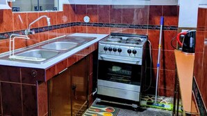 A kitchen with a stove, sink, wooden cabinets, and a tiled backsplash. - Strategic and centrally located apartment in Magdalena del Mar (Magdalena del Mar)